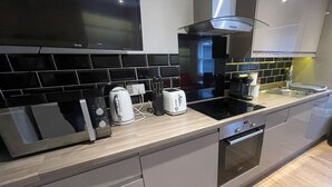 A modern kitchen with a built-in oven, a microwave, and a toaster. - Modern en-suite Studio in the Heart of Mill Road (Cambridge)
