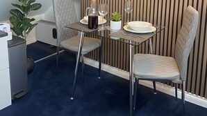 A small dining area with a table set for two, a potted plant, and a framed picture on the wall. - Modern ensuite Studio Retreat off Vibrant Mill Rd (Cambridge)