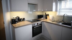 A compact kitchen with white cabinets, a built-in oven, a microwave, a toaster, and a sink. - Modern Studio - just off Mill Rd nr train station (Cambridge)