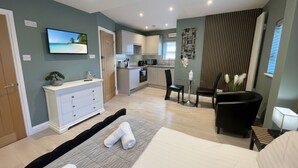 A modern hotel room with a bed, a desk, a chair, a small kitchen area, and a dining table. - Modern Studio - just off Mill Rd nr train station (Cambridge)