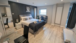 A modern bedroom with a bed, bedside tables, a desk, and a chair. - Modern Studio - just off Mill Rd nr train station (Cambridge)