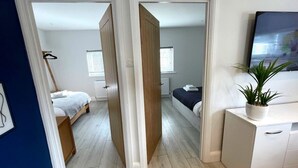 A modern bedroom with a bed, a desk, and a potted plant.
