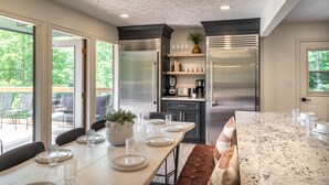 Una cocina moderna con electrodomésticos de acero inoxidable, un comedor con mesa de mármol y vistas al exterior.