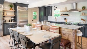 Una cocina moderna con armarios oscuros, una isla central y un comedor con una mesa dispuesta para cuatro.