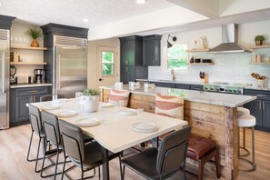 A modern kitchen with dark cabinetry, a central island, and a dining area with a table set for four.