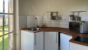 Eine Küche mit weißen Schränken, einer Edelstahl-Spüle, einer Mikrowelle und einem Einbauofen.