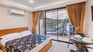 Une chambre d’hôtel avec un lit, une petite table et une chaise, ainsi qu’une grande fenêtre avec des rideaux.