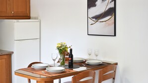 Une table à manger dressée avec des assiettes, des verres, une bouteille et un vase rempli de fleurs.
