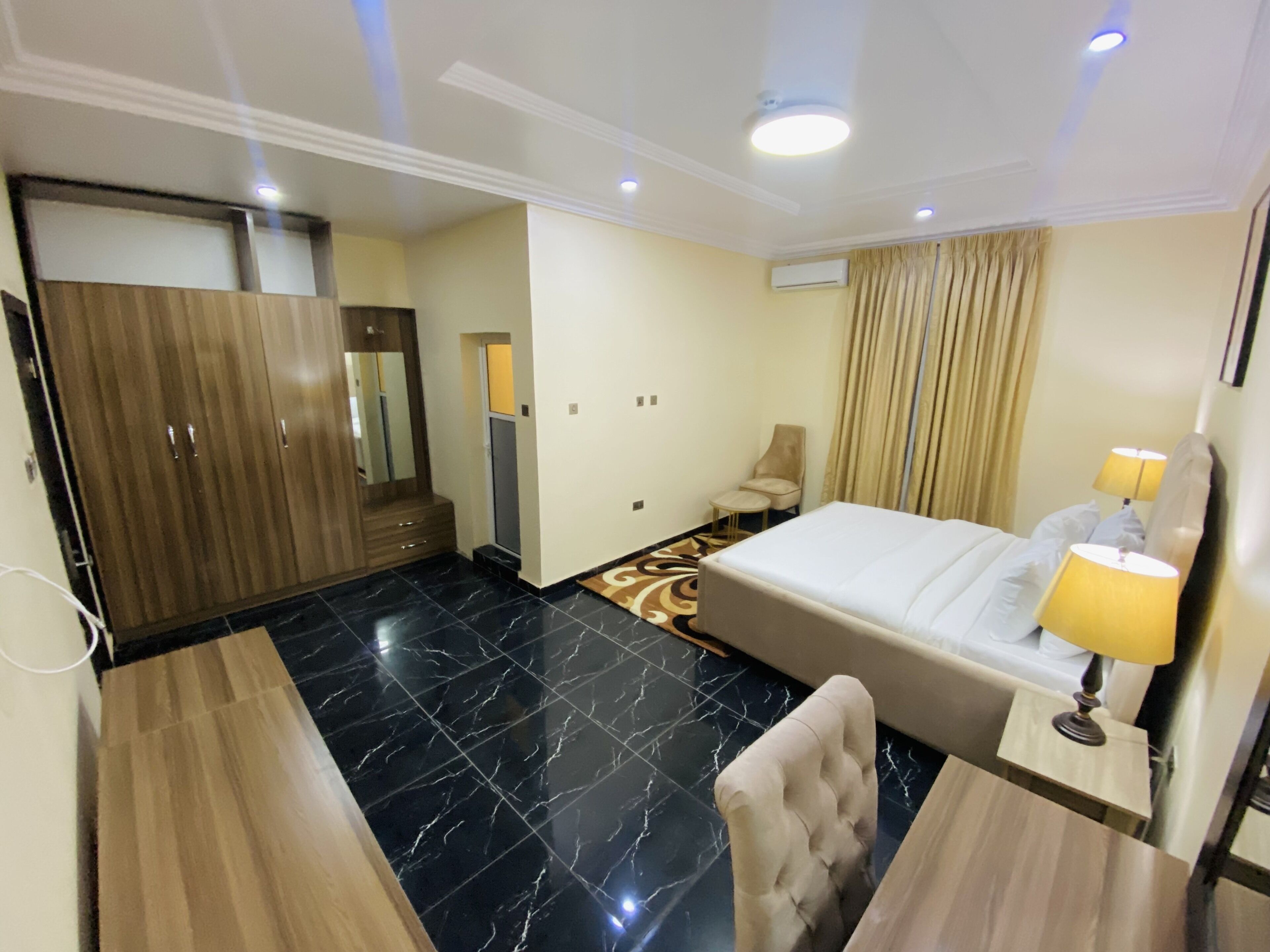Une chambre d’hôtel comprenant un lit, une table de chevet, une lampe, une chaise, une armoire et un miroir.