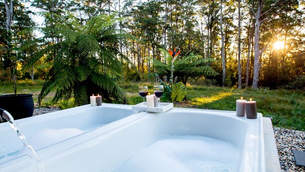 Ein Whirlpool mit Kerzen und Blick auf eine bewaldete Landschaft.