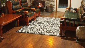 Ein gemütliches Wohnzimmer mit Steinwand, Kamin, Ledersofas und einem Holztisch.