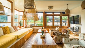 Una habitación acogedora con un ventanal grande, un banco de madera, una mesa y varias sillas.