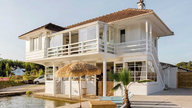 Un edificio de dos pisos con balcón, piscina y zona de estar al aire libre.