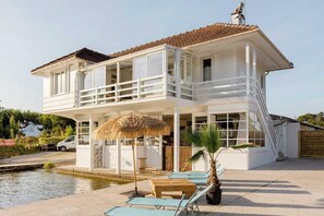 A two-story building with a balcony, a pool, and outdoor seating.