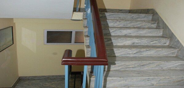 A staircase with marble steps and a wooden handrail. - MeroStay 192 Home HTS (Kathmandu)