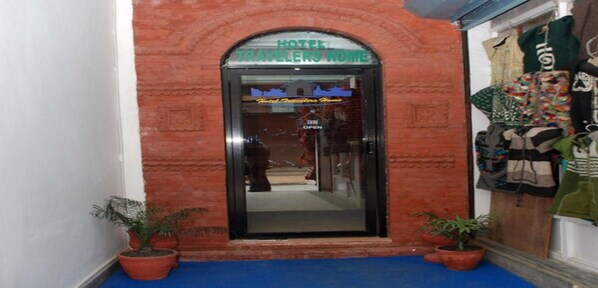 A hotel entrance with a sign reading "HOTEL TRAVELERS HOME" and a glass door.