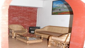 A living room with wicker furniture, a brick wall, and a framed picture on the wall. - MeroStay 192 Home HTS (Kathmandu)