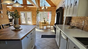 Une cuisine moderne avec des meubles en bois, un îlot central et un coin repas comprenant une table et des chaises.
