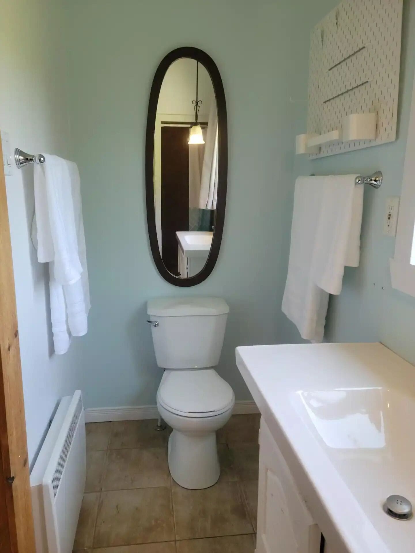 A bathroom with a toilet, sink, and mirror.
