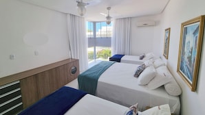 Hotellihuone, jossa on kaksi sänkyä, kattotuuletin, ikkuna verhoilla ja taulu seinällä.