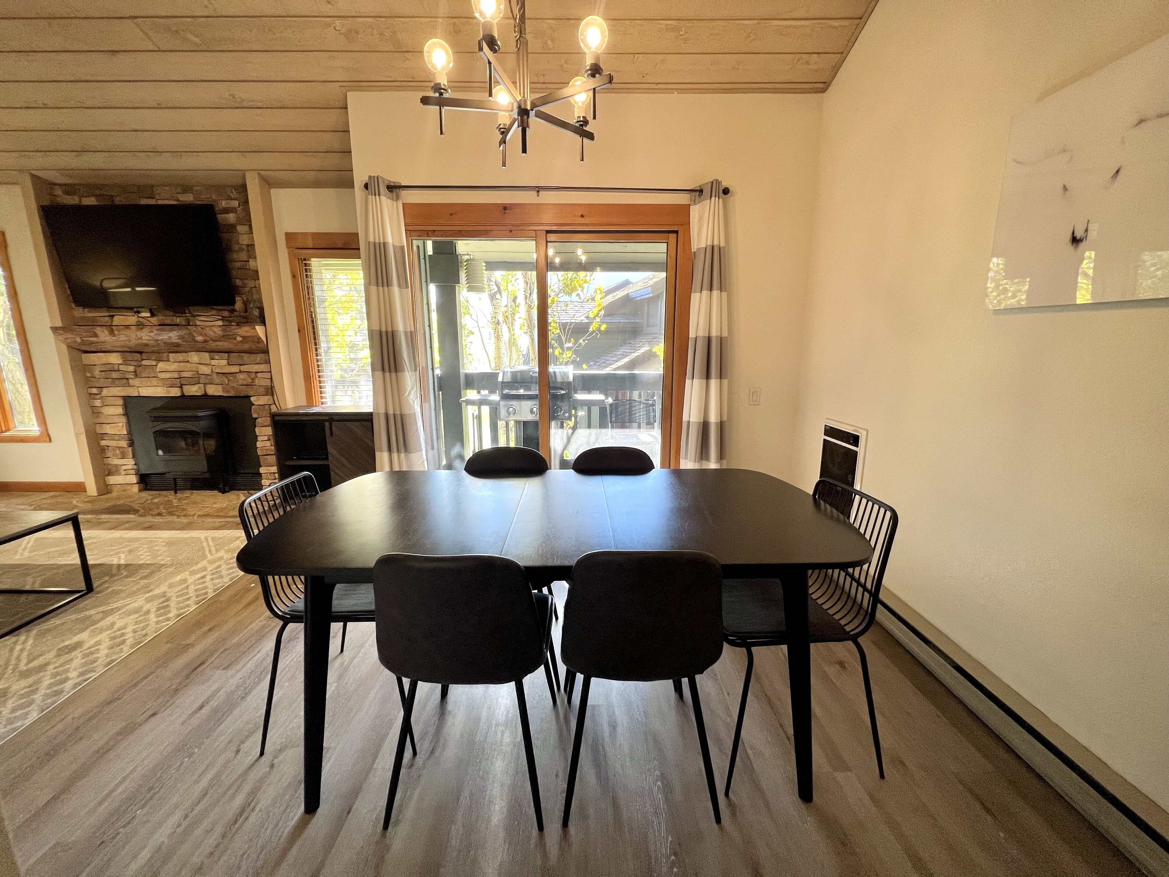 A dining area with a stone fireplace, a large table, and chairs.