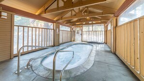 En indendørs swimmingpool med træbjælker og gelændere.