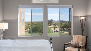 Ein Schlafzimmer mit großem Fenster, einem Bett, einem Sessel und einer Lampe.