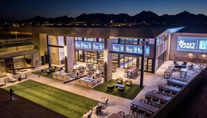 A modern outdoor lounge area with multiple seating arrangements and a visible restaurant sign.