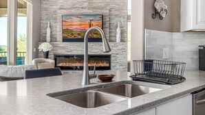 Eine moderne Küche mit einer Granitarbeitsplatte, einer Edelstahlspüle und einem Kamin.