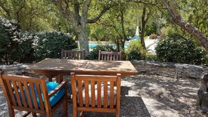 An outdoor wooden table and chairs with a stone wall and greenery in the background. - Prestigious South-Facing Villa with Pool – Absolute Calm on the French Riviera (Le Muy)