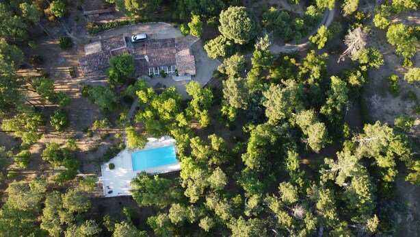 An aerial view of a property with a swimming pool surrounded by trees, a parking area, and a building with a tiled roof. - Prestigious South-Facing Villa with Pool – Absolute Calm on the French Riviera (Le Muy)