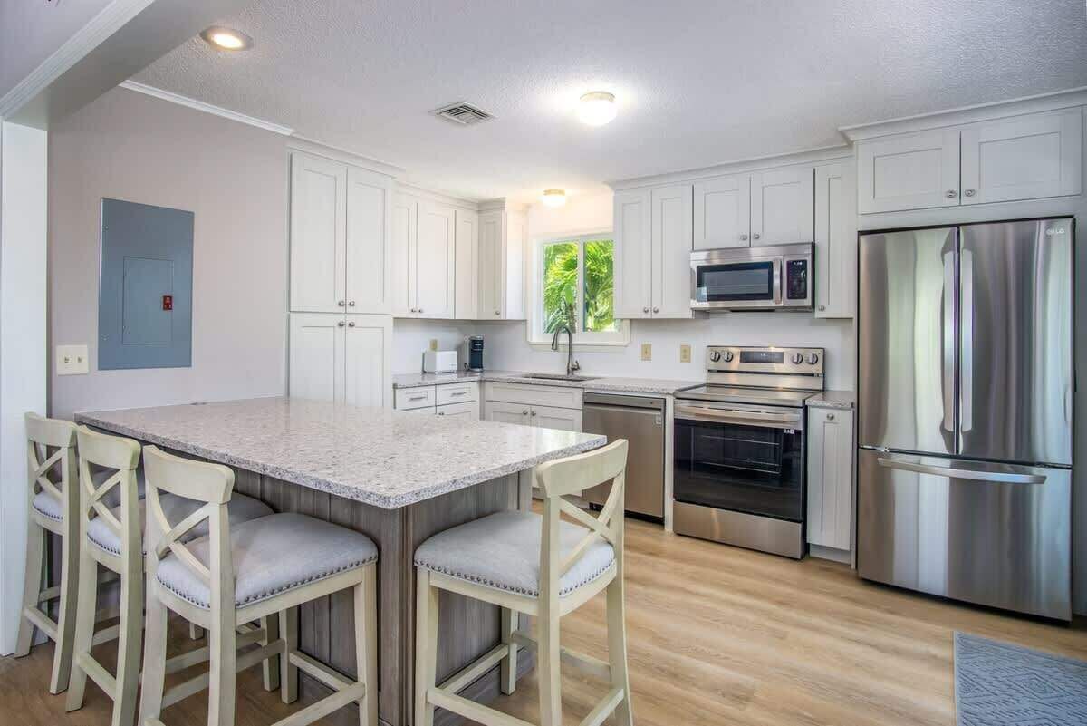 A modern kitchen with white cabinets, stainless steel appliances, and a central island with bar stools.