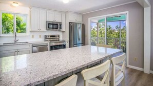 A modern kitchen with white cabinets, stainless steel appliances, and a large island with bar stools.