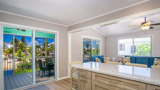 A spacious kitchen with a large island, sliding glass doors to a balcony, and a ceiling fan.