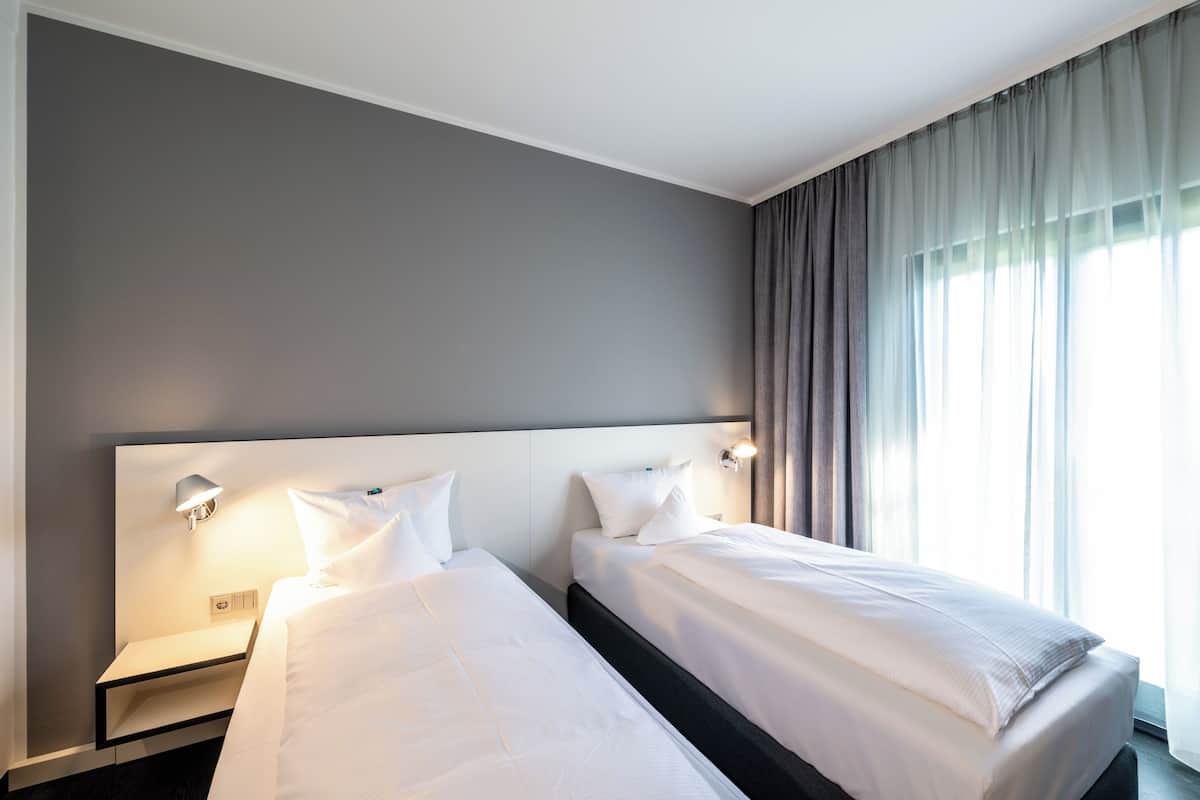 Ein Hotelzimmer mit zwei Betten, einem Nachttisch und einer Wandlampe.