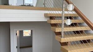 Una escalera moderna con escalones de madera y barandillas de metal, que conduce a un piso superior.