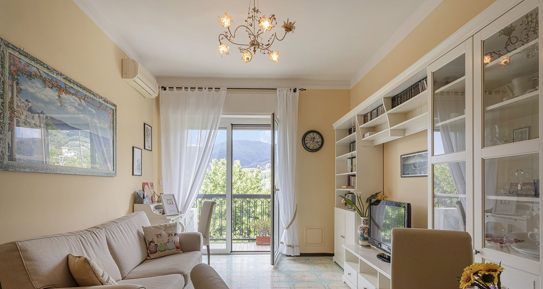 Un salon avec un canapé, une table à manger sur laquelle se trouve un plateau, une bibliothèque et une vue sur l’extérieur.