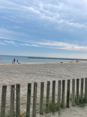 Une plage de sable avec une clôture en bois au premier plan.