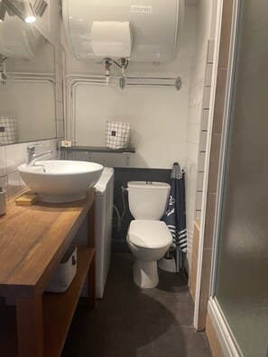 Une petite salle de bain avec un lavabo blanc, des toilettes et un espace douche.