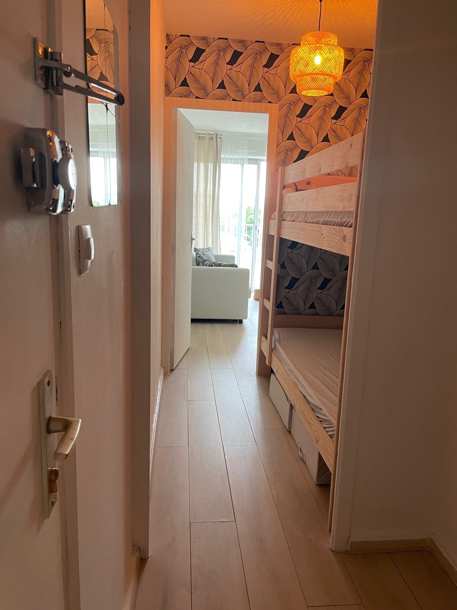 A hallway with a bunk bed, a door with a lock, and a hanging light fixture.
