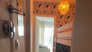 Un pasillo con una litera, una puerta con cerradura y una lámpara colgante.