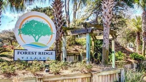 Un letrero de madera con el logo de un árbol y la inscripción "Forest Ridge Village".