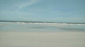 Una playa con una amplia orilla de arena y olas suaves.