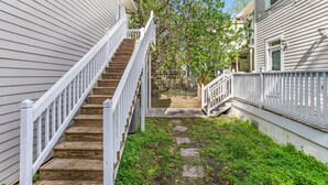 A wooden staircase leading to a porch with white railings, surrounded by greenery and a fence. - King Bed + Walking Distance to Forsyth Park by Lucky Savannah (Savannah)