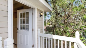 A white front door with a glass panel, a white picket fence, and a tree in the background. - King Bed + Walking Distance to Forsyth Park by Lucky Savannah (Savannah)