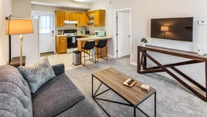 A modern living room with a sofa, coffee table, and a TV mounted on the wall. - King Bed + Walking Distance to Forsyth Park by Lucky Savannah (Savannah)