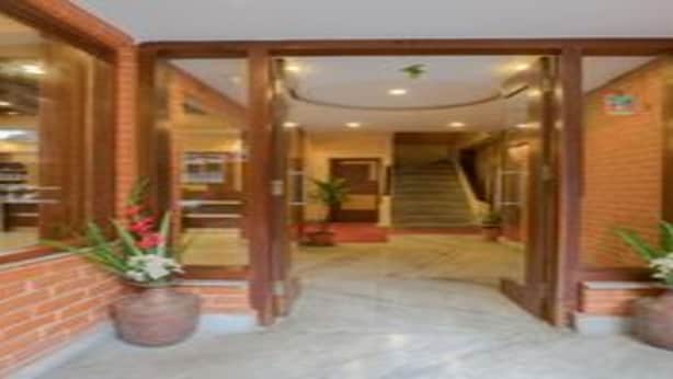 Una entrada de hotel con fachada de ladrillo, puerta de cristal y una escalera que conduce al piso superior.