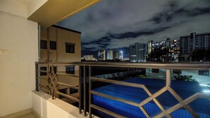Un balcon avec des balustrades en métal donnant sur une vue panoramique de la ville la nuit.