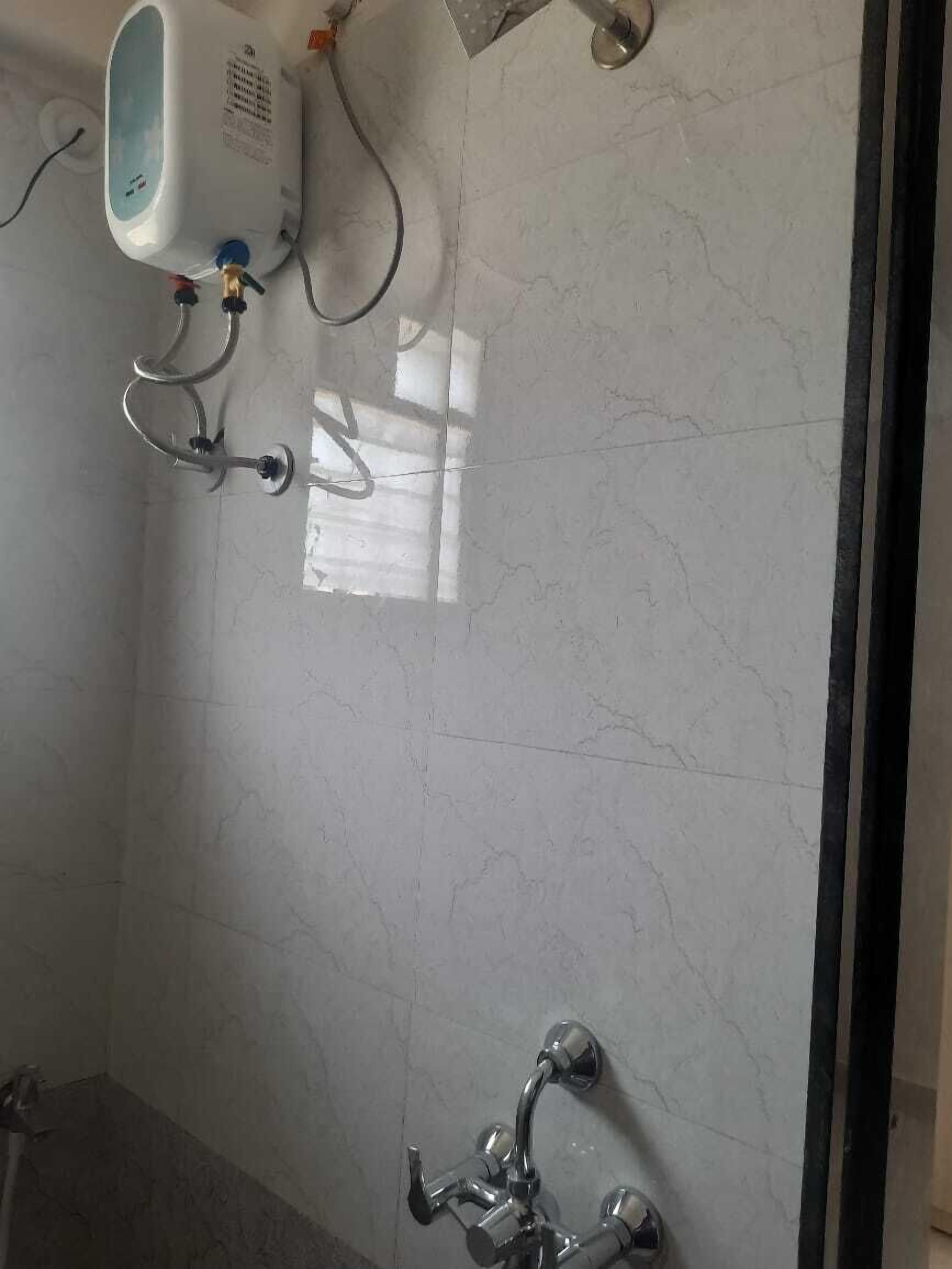A bathroom with a marble floor, a handheld showerhead, and a wall-mounted water heater.