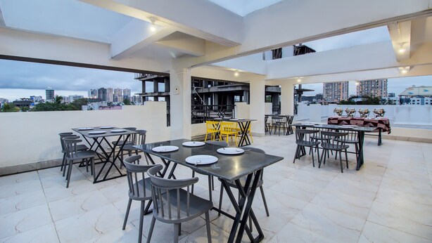 Un espace de restauration en plein air doté de nombreuses tables et chaises, offrant une vue sur le paysage urbain et présentant un design architectural moderne.